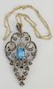 18 karat gold and silver lavalier pendant with center emerald cut blue stone measuring 11 x 14 mm, surrounded by approximately 1 ct....