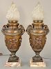 Pair of bronze torchiere form figural table lamps, 
frosted flame form shades over bronze urn body with rams head handles and molded...