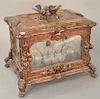 Black forest tantalus,  having rectangular lift-top with two bird finial above hinged glass case with fruit and leaf accents, having...