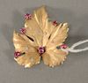 14 karat leaf pin set with six small red stone and five small diamonds, 7.6 grams.