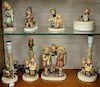 Eight large Hummel figurines to include three lamps, one with girls; a round box; boy on sled; candlelight; and two kids with donkey...