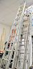 Group of three aluminum extension ladders.