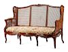 A French Provincial Carved Oak and Caned Settee