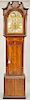 Mahogany tall case clock, having carved finials with fretwork backed with cloth over tombstone dial flanked by fluted columns on case with panel inlay
