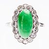A JADE AND DIAMOND RING, the oval cabochon cut jade set wit