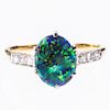 A BLACK OPAL AND DIAMOND RING, the oval cut opal set betwee