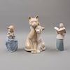 Lote de 3 figuras decorativas. España. 1987. En porcelana, una Nao. Consta de: monaguillo, niña con perro y pareja de gatos.
