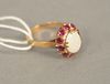 14K gold ring set with oval opal surrounded by red stones, size 7.