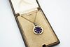 AN AMETHYST AND DIAMOND PENDANT, the round cut amethyst within a surround o