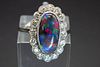 A PLATINUM, BLACK OPAL AND DIAMOND RING, the oval cut opal set within a sca