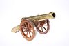 A DECORATIVE BRASS MODEL CANNON, the barrel moving on a wooden carriage, th