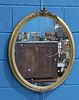 A VICTORIAN GILT-COMPOSITION OVAL MIRROR, with foliate crestings and beaded