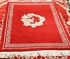 A CHINESE RUG, centred by a dragon, on a red ground. 204cm by 122cm