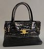 lana Marks shiny black crocodile/alligator handbag with gold tone buckle and clasps, ht. 9", wd. 13", dp. 5", light wear and scratches from use.