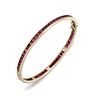 A RUBY BANGLE
 The hinged bangle, set with a conti