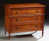 French Provincial Louis XVI Style Carved Cherry Commode, 20th c., the shaped stepped top over three drawers flanked by reeded round...