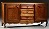 French Provincial Louis XV Style Carved Cherry Sideboard, early 20th c., the stepped canted corner rounded edge top over a central b...