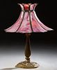 American Gilt Spelter Table Lamp, c. 1920, on a tapered baluster support to a relief decorated circular base, with a later pink floriform slag glass s