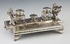 Silver Plated Louis XV Style Inkwell, 19th c., by Reed & Barton, with a reeded edge, the rear with putti and two crystal inkwells, behind a pen tray, 