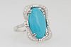 Lady's 14K White Gold Dinner Ring, with an oval 5.6 ct. cabochon turquoise within an undulating pierced diamond mounted border, the shoulders of the b