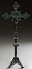 Bronze Table Crucifix, early 20th c., with pierced floral decoration on a knopped support, to a tripodal base with scroll decorated legs, H.- 24 1/2 i