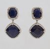 Pair of 18K White Gold Pendant Earrings, with a cushion cut blue sapphire atop a border of round diamonds, suspending a single diamond mounted link an