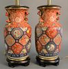 Pair of Imari porcelain vases, each mounted as a lamp with painted and applied floral decoration on a stained wood stand, vase 17 1/2", with stand 26"