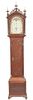 Cherry Tall Case Clock, having three brass finials and carved fretwork atop of tombstone door flanked by columns on case with arch t...