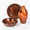 Redware Flask and Two Small Redware Dishes, 19th century, the flask with red-orange glaze and three manganese splotches, the plates wit