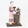 Folk Art Paint-decorated Carving of a Teacher, the figure of a woman dressed in a pink dress holding a book and a broom standing next t