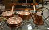 Group of eight copper and brass handled cookware, center island pot hanger included, some stamped "Williams Sonoma, France".