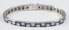Platinum Diamond Bracelet
set with thirty-four diamonds, surrounded by Greek key design, with square blue sapphires, (one small sapphire missing),
Pat