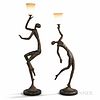 Two Giacometti-inspired Patinated Metal Figural Floor Lamps, mid-20th century, dancing figures hold urn-shaped frosted glass shades, un
