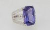 Lady's Platinum Dinner Ring, with a 13.97 carat emerald cut tanzanite atop pierced diamond mounted shoulders of the band, total diamond weight- 1.02 c
