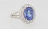 Lady's Platinum Dinner Ring, with an oval 2.76 carat tanzanite atop a double graduated concentric border of small round diamonds, the split shoulders 