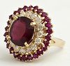 Lady's 14K Yellow Gold Dinner Ring, with an oval 9.61 carat ruby, atop a border of round diamonds, within an outer border of round rubies, total diamo