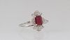 Lady's Platinum Dinner Ring, with a rectangular 1.23 ct. ruby, atop a floriform border of round diamonds and demilune diamond mounted lugs, the should