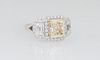 Lady's 18K White Gold Dinner Ring, with a light yellow 2.42 ct. emerald cut diamond atop a border of round diamonds, flanked by lugs with emerald cut 