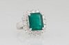 Lady's 18K White Gold Dinner Ring, with a 6.43 ct. emerald atop a border of round diamonds, total diamond wt.- 1.34 cts., Size 5 1/2, with appraisal.