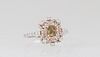 Lady's 18K White Gold Dinner Ring, with a .53 ct. yellowish-green cushion cut diamond, atop a border of pink diamonds and a pierced outer border of pi