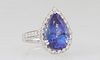 Lady's Platinum Dinner Ring, with an 8.74 ct. pear shaped tanzanite atop a conforming border of round diamonds, the shoulders of the band with graduat