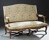 French Louis XV Style Carved Walnut Settee, early 20th c., the arched upholstered canted back over upholstered arms and a serpentine upholstered seat,