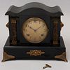 Reloj de chimenea. Estados Unidos. Siglo XX. Estilo Napoleón III. Elaborado en madera color negro con aplicación de metal dorado.