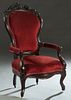 American Victorian Carved Mahogany Upholstered Armchair, late 19th c., the arched fruit and flower carved crestrail over a shield shaped back, to curv