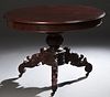 American Carved Mahogany Center Table, early 20th c., the ogee edge circular top on an urn form support to tripodal grape carved scrolled legs on cast
