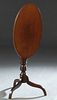 English Carved Mahogany Oval Tilt Top Candlestand, early 20th c., on a turned baluster urn form support to tripodal curved legs, H.- 28 3/4 in., W.- 2