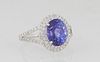 Lady's Platinum Dinner Ring, with an oval 4.05 tanzanite atop a conforming double graduated border of round diamonds, the split shoulders of the band 