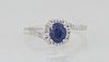Lady's Platinum Dinner Ring, with an oval 1.19 ct. blue sapphire atop a border of round diamonds, the shoulders of the bypass band also mounted with t
