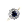 An 18ct gold sapphire and diamond cluster ring. The circular-shape sapphire, within a brilliant-cut