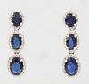 Pair of 14K White Gold Pendant Earrings, each with three graduated oval links with an oval blue sapphire atop a border of tiny round diamonds, total s